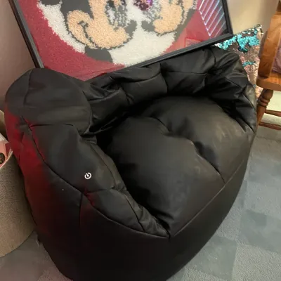 Sale Photo Thumbnail #238: Black faux leather modern bean bag lounge chair featuring an integrated power button symbol, positioned below framed Mickey Mouse art.