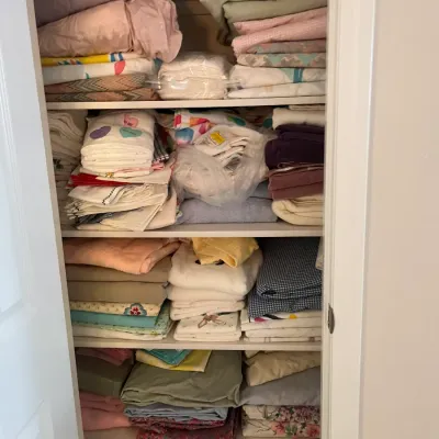 Sale Photo Thumbnail #217: Linen closet fully stocked with stacked bed sheets, pillowcases, blankets, and bath towels in various colors and patterns.
