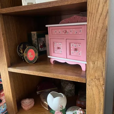 Sale Photo Thumbnail #187: Pink floral wooden miniature jewelry armoire, small decorative boxes, and ceramic trinkets displayed on wooden shelving.