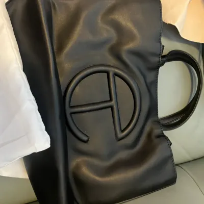Sale Photo Thumbnail #51: Black Telfar Shopping Bag featuring the raised signature embossed logo, top handles, and an accompanying white dust bag.