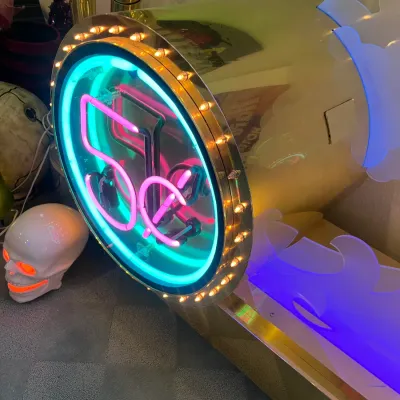 Sale Photo Thumbnail #154: Vintage Studio 54 themed neon sign integrated into a polished brass housing with marquee perimeter lights, displayed alongside decorative novelty items.