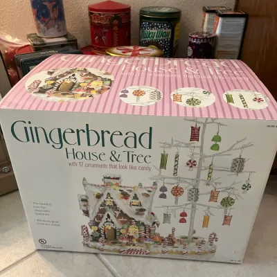 Sale Photo Thumbnail #5: Vintage holiday Gingerbread House & Tree set in original box, featuring glowing windows and 17 candy-style ornaments, with assorted decorative tins in the background.