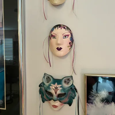 Sale Photo Thumbnail #44: Set of three vintage ceramic wall masks, including Art Deco style faces and a green cat-like masquerade mask with colorful ribbon accents.