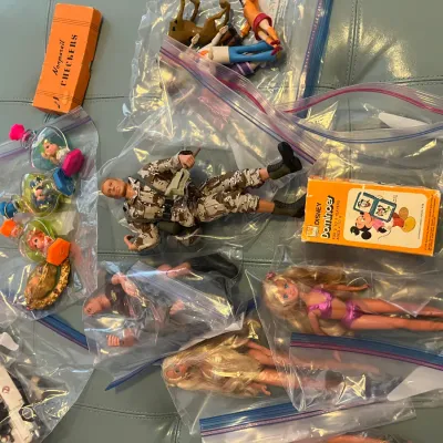 Sale Photo Thumbnail #141: Assorted vintage toys and action figures packaged in plastic storage bags, including GI Joe figures, Barbie dolls, Scooby-Doo figurines, and boxed tabletop games.