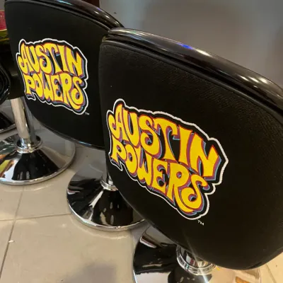 Sale Photo Thumbnail #58: Pair of novelty Austin Powers swivel bar stools with black vinyl upholstery and chrome pedestal bases, circa late 1990s.