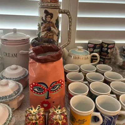Sale Photo Thumbnail #17: Collection of assorted ceramics and drinkware, including a tall German beer stein, novel face-painted vase, novelty mug set, and Christmas gift-shaped salt and pepper shakers.
