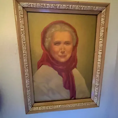 Sale Photo Thumbnail #87: Framed vintage portrait painting depicting an elderly woman wearing a red headscarf, presented in a decorative carved wood frame.