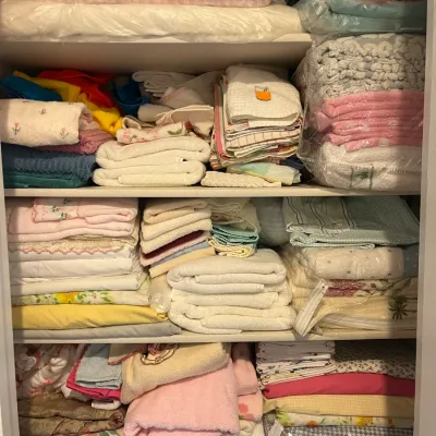 Sale Photo Thumbnail #182: Linen closet filled with neatly stacked vintage bath towels, hand towels, washcloths, and bed sheets in pastel colors and floral patterns.