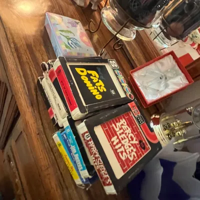 Sale Photo Thumbnail #100: Collection of vintage 8-track tapes, including titles by Fats Domino, Percy Sledge, and Jim Reeves, arranged on a wooden surface.