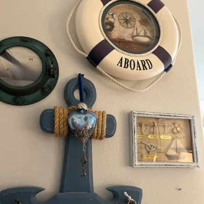 Sale Photo Thumbnail #198: Nautical-themed wall decor collection, including a life preserver clock, a porthole-framed picture, a wooden anchor coat rack, and a shadow box display of sailor's knots.