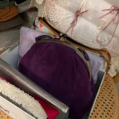 Sale Photo Thumbnail #174: Storage box containing vintage purses, including a deep purple suede kiss-lock frame bag and an embellished white beaded clutch.