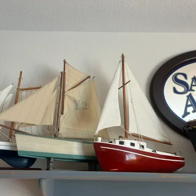 Sale Photo Thumbnail #209: Collection of wooden model sailboats displayed on a shelf alongside a Samuel Adams bar mirror.