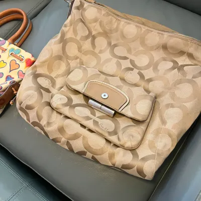 Sale Photo Thumbnail #47: Beige Coach Optic Signature C jacquard shoulder bag featuring a front flap pocket with silver-tone hardware accents, resting on a leather sofa.