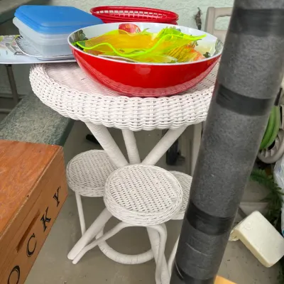 Sale Photo Thumbnail #145: White painted wicker plant stand or small side table holding assortment of plastic housewares and serving bowls.