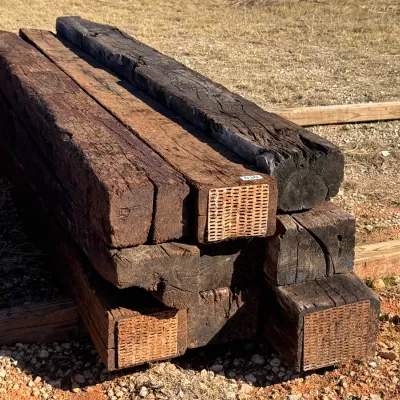 Sale Photo Thumbnail #17: Stack of heavy-duty wooden railroad ties featuring metal end plates, suitable for landscaping or outdoor construction projects.