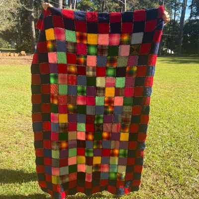 Sale Photo Thumbnail #8: Handmade patchwork afghan blanket featuring a colorful grid pattern of yarn squares with a navy blue and red border 
