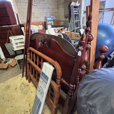 Sale Photo Thumbnail #20: Disassembled traditional dark wood four-poster bed frame stored in a garage, accompanied by various household items and furniture pieces.
