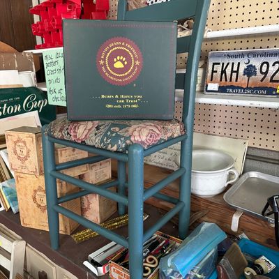 Sale Photo Thumbnail #78: Boyds Bears & Friends Bearstone Collection boxed collectible resting on a teal painted wooden side chair with floral upholstered seat.