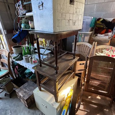 Sale Photo Thumbnail #30: Collection of vintage furniture and household items, including a cane-back chair, stacked wooden tables, and rustic storage trunks.