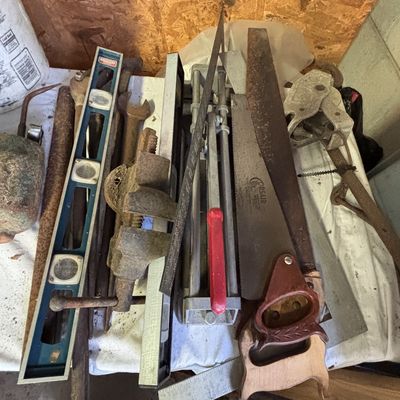 Sale Photo Thumbnail #24: Assortment of vintage hand tools including a Corsair hand saw, Stanley level, metal bench vise, framing square, and various rusted wrenches.