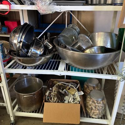 Sale Photo Thumbnail #86: White wire rolling shelving unit filled with stainless steel mixing bowls, pots, bakeware, a box of extension cords, and glass jars full of wine corks.