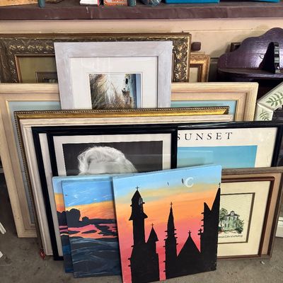 Sale Photo Thumbnail #83: Large collection of framed and unframed artwork, including various paintings, prints, posters, and decorative picture frames stacked together.