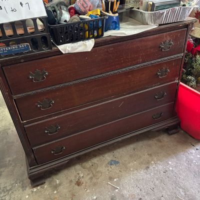 Sale Photo Thumbnail #49: Vintage dark stain wooden four-drawer chest featuring decorative carved trim and batwing bail pull handles, loaded with assorted office supplies on top.