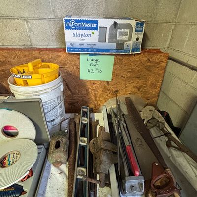Sale Photo Thumbnail #22: Assortment of vintage hand tools including a level, hand saws, bench vise, wrenches, and a boxed PostMaster mailbox.