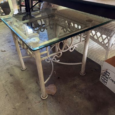Sale Photo Thumbnail #90: Vintage off-white wrought iron end table with a clear glass top, featuring decorative scrollwork detail.