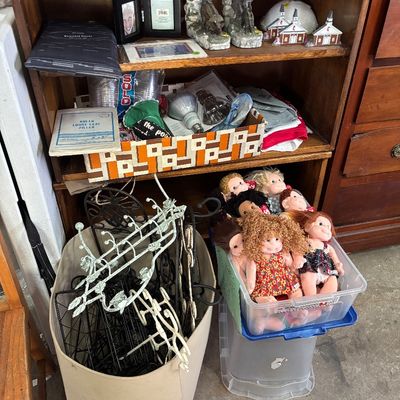 Sale Photo Thumbnail #47: Wooden bookcase filled with assorted household goods, picture frames, and miniature decor, alongside plastic storage bins containing metal racks and plush dolls.