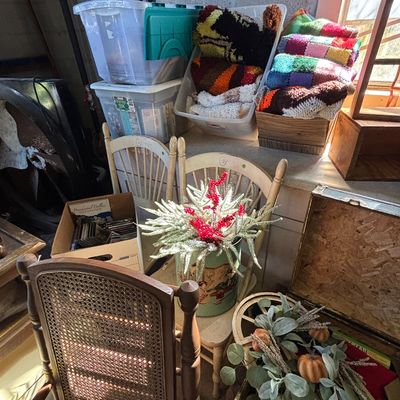 Sale Photo Thumbnail #15: Collection of household goods including a cane-back dining chair, wooden spindle-back chairs, vintage crocheted blankets, and decorative floral arrangements.