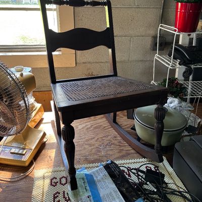 Sale Photo Thumbnail #96: Vintage dark wood rocking chair featuring a woven cane seat, turned legs, and a spindle top rail.