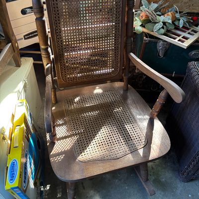 Sale Photo Thumbnail #31: Vintage wooden rocking chair featuring a woven cane backrest and seat panel.