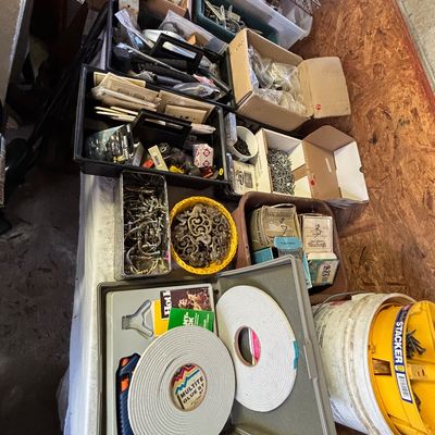 Sale Photo Thumbnail #23: Assortment of workshop, crafting, and hardware supplies including rolls of weatherstripping, hot glue guns, brass drawer pulls, and sorted fasteners.