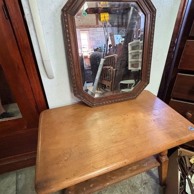 Sale Photo Thumbnail #16: Octagonal framed wall mirror with carved trim resting atop a mid-century style wooden side table with lower shelf.