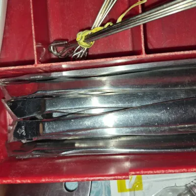 Sale Photo Thumbnail #686: Collection of vintage stainless steel fondue forks stamped "Japan" organized inside a red plastic tray compartment.