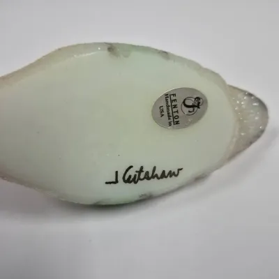 Sale Photo Thumbnail #217: Underside of a Fenton art glass figurine showing the original foil label and artist signature J. Cutshaw.