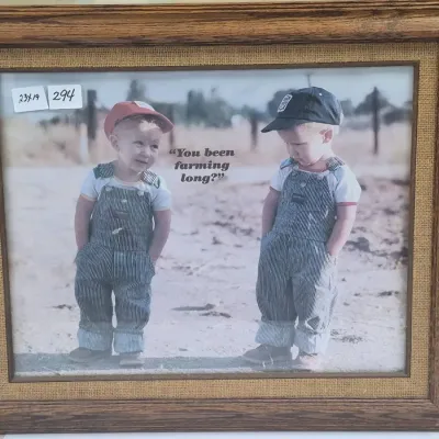 Sale Photo Thumbnail #523: Framed nostalgic poster titled 'You been farming long?' featuring two toddlers in OshKosh overalls, set in a rustic wood frame with a burlap liner.