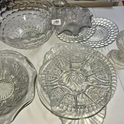 Sale Photo Thumbnail #332: Collection of vintage clear pressed glass tableware including a large thumbprint bowl, serving platters, ruffled bowls, and a pedestal candy dish.