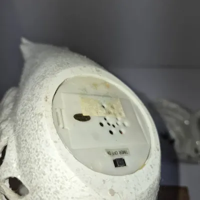 Sale Photo Thumbnail #230: Underside of a white ceramic decorative item featuring an integrated battery compartment with timer, off, and on switch settings.