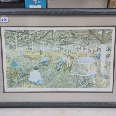 Sale Photo Thumbnail #479: Framed and matted art print titled 'Carolina Tobacco' by Doris & Jerry Locklair, depicting a bustling tobacco warehouse scene.