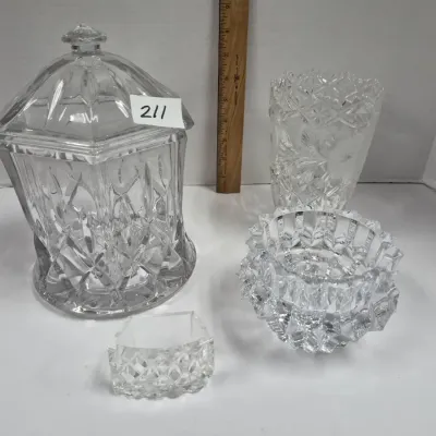 Sale Photo Thumbnail #363: Collection of clear cut glass tabletop items including a large lid jar, two vases, and a small decorative bowl, shown next to a wooden ruler for scale.