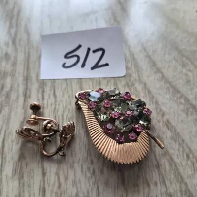 Sale Photo Thumbnail #883: Vintage gold-tone rhinestone leaf brooch with pink and smoky gray stones, accompanied by a pair of gold-tone screw-back shell earrings.