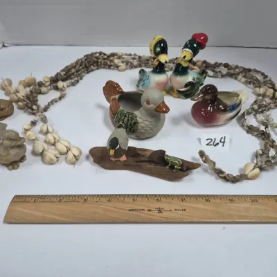 Sale Photo Thumbnail #449: Collection of vintage duck figurines, planters, and shell leis, including hand-painted ceramic and resin birds.