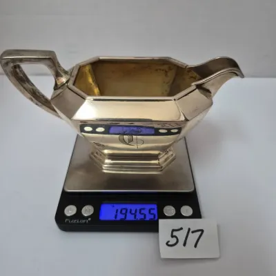 Sale Photo Thumbnail #890: Monogrammed sterling silver creamer, weighing 194.55 grams on a digital scale.