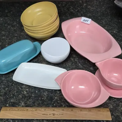 Sale Photo Thumbnail #671: Collection of mid-century vintage Melmac melamine tableware, including pink serving pieces, yellow bowls, a turquoise butter dish, and a small white bowl.