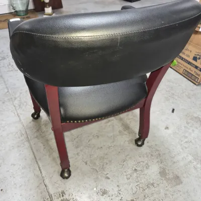 Sale Photo Thumbnail #13: Vintage executive swivel captain's chair with black faux leather upholstery, reddish wood frame, nailhead trim, and brass caster feet.