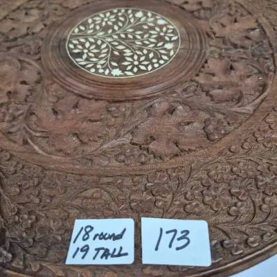 Sale Photo Thumbnail #299: Intricately hand-carved Anglo-Indian or Anglo-Eastern wooden side table top featuring a floral and leaf motif with a bone inlay center medallion, measuring 18 inches round and 19 inches tall.