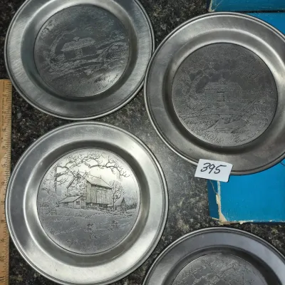 Sale Photo Thumbnail #691: Set of four Eric Sloane etched pewter collector plates featuring rural landscape scenes, complete with original boxes.