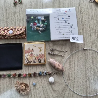 Sale Photo Thumbnail #865: An assortment of vintage jewelry and accessories, featuring a boxed Nativity Story beaded bracelet, a floral powder compact, gemstone link bracelet, and a silver wire choker necklace.
